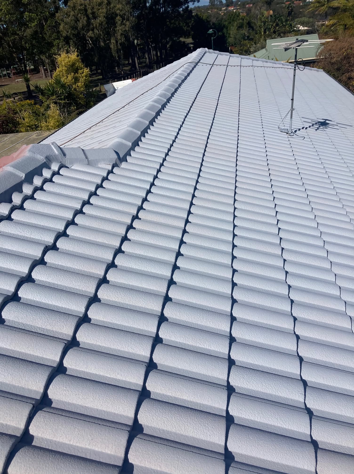 Brilliant white cool-roof coating on full residential tile roof, aerial view